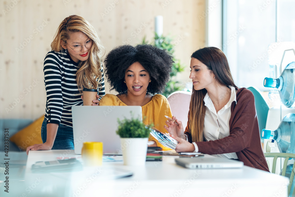 Casual multiethnic business women working with laptops while talking of they new projects together in coworking place.